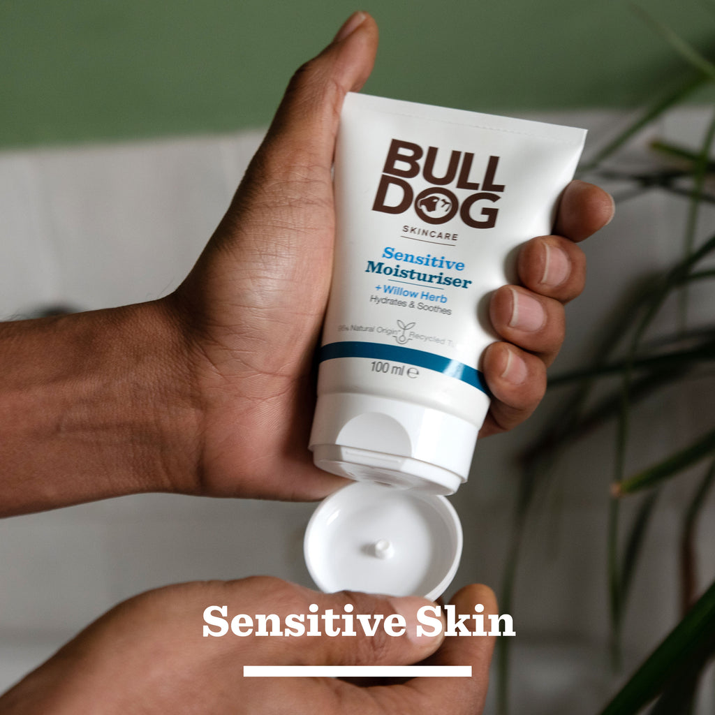 A person’s hands holding an open tube from the Sensitive Duo Set, with “Sensitive Skin” text below. The blurred green plants in the background emphasize it as a thoughtful gift for men who appreciate gentle care.