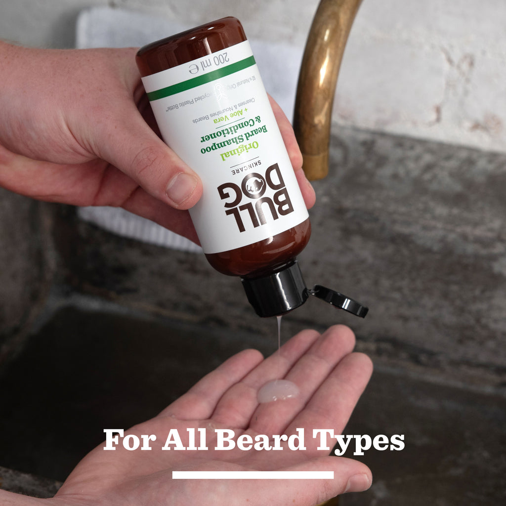 A person dispenses beard shampoo and conditioner from the Original Ultimate Beard Care Kit onto their palm over a sink. Text at the bottom reads, For All Beard Types.