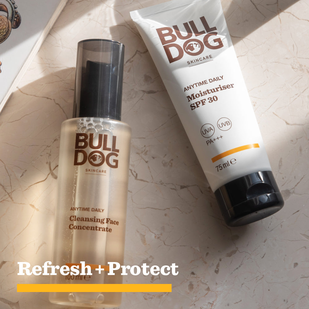 Two Bulldog Skincare products, Anytime Daily Cleansing Face Concentrate with Fruit Alpha Hydroxy Acids and a Moisturiser SPF 30 made with natural origin ingredients, sit on a beige surface as sunlight casts shadows. Refresh + Protect appears below.